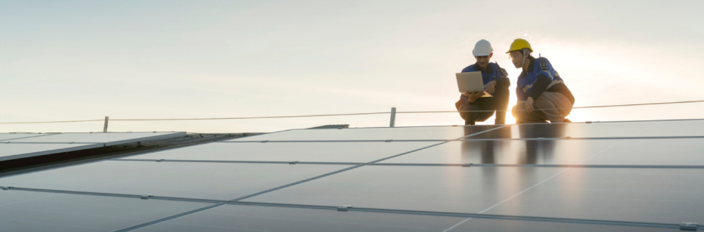 Two solar panel technicians reviewing a roof system