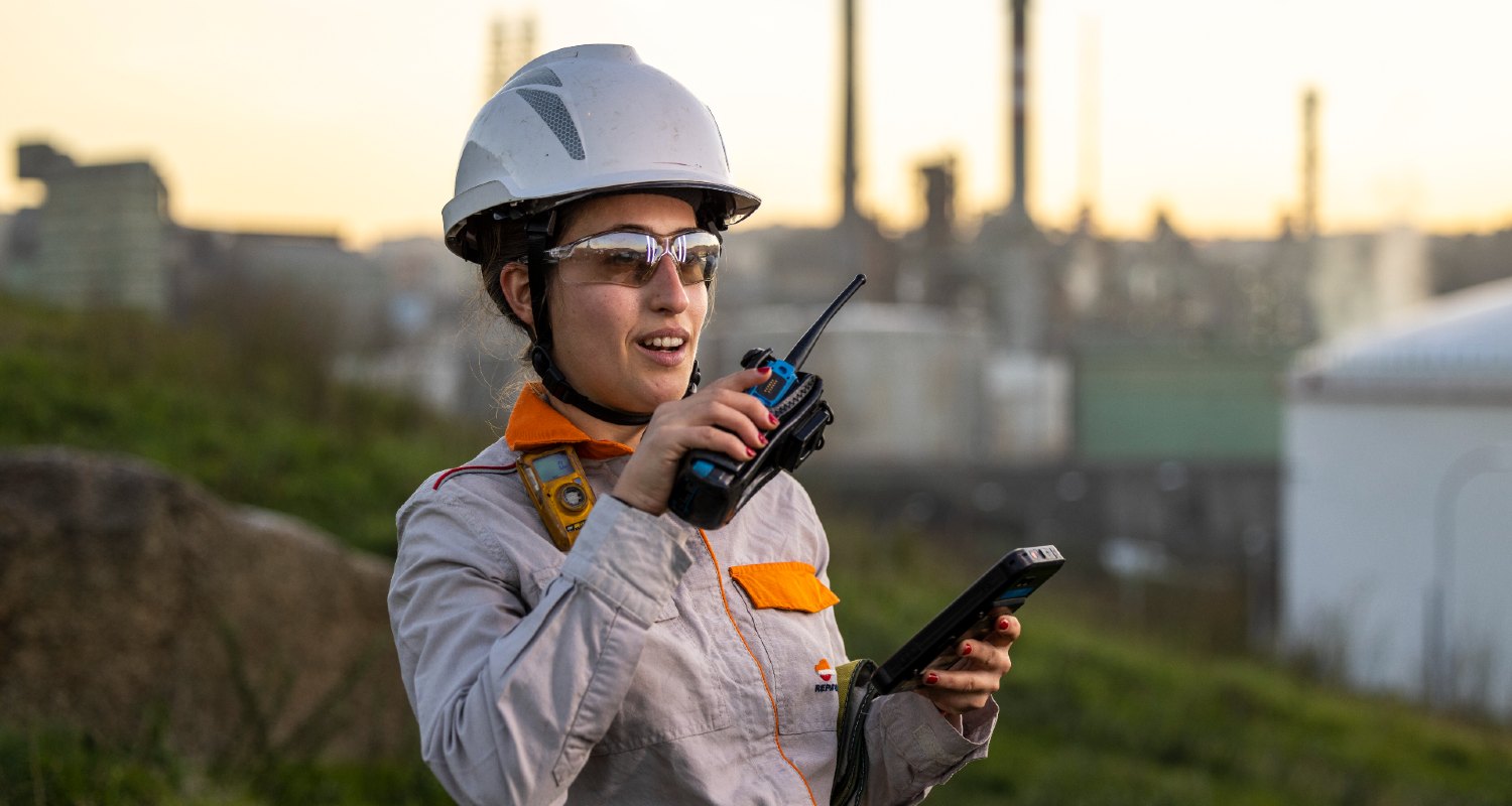 A worker at an industrial complex talking on a walkie-talkie