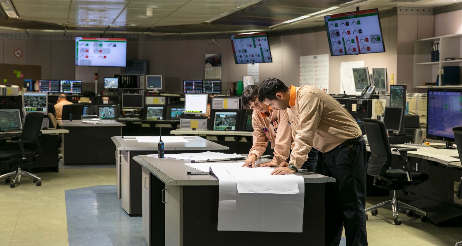 Dos trabajadores de un complejo industrial mirando un plano en una mesa
