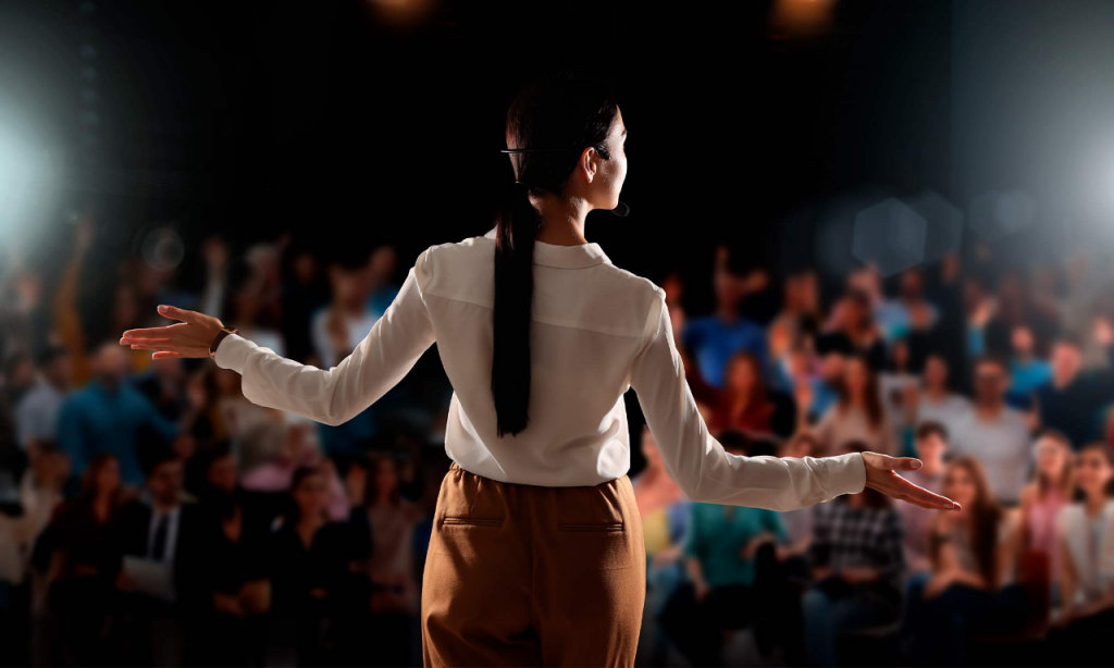 A female speaker in front of a crowd during a talk