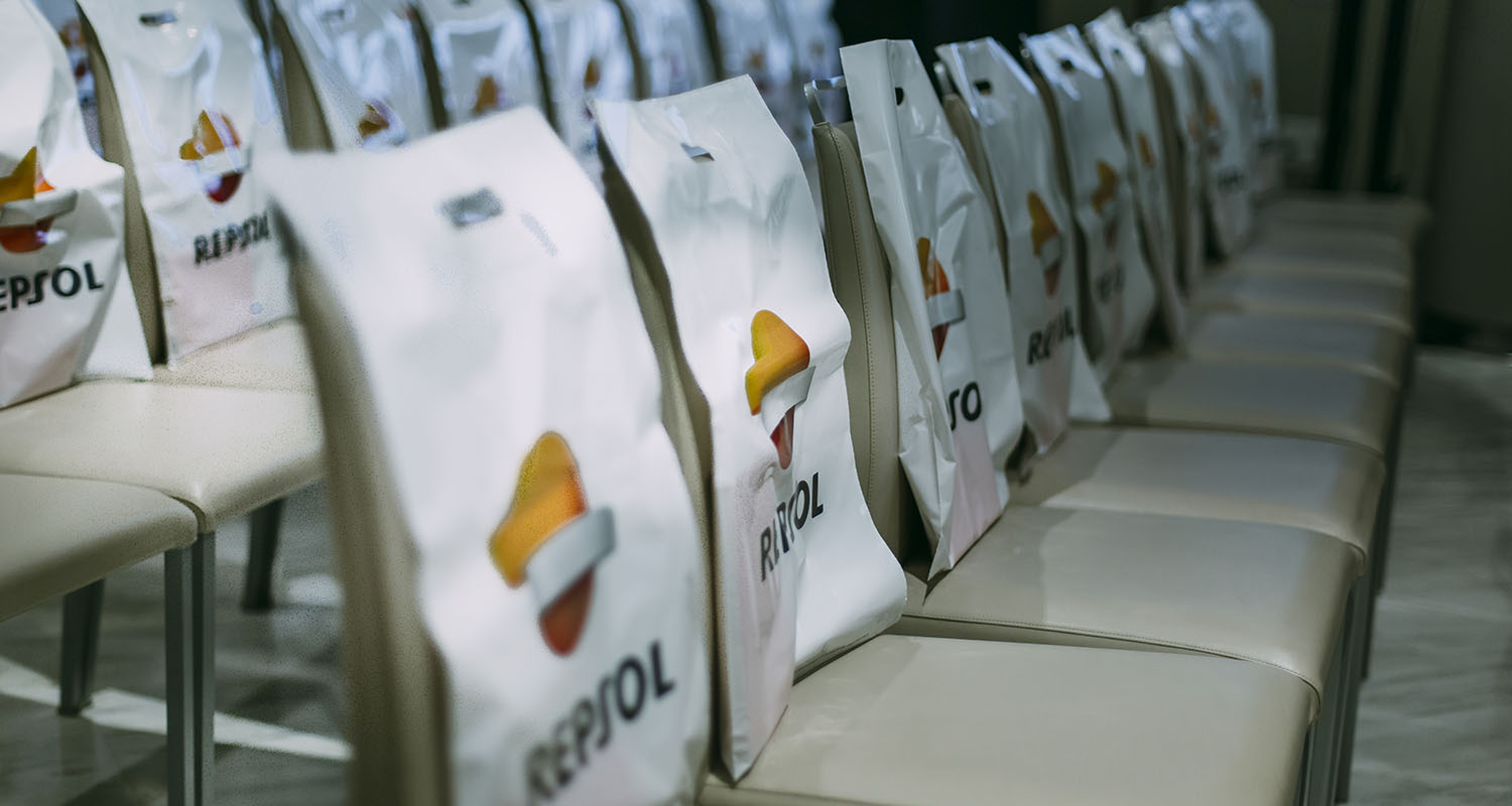 A line of multiple chairs with a white cover with the Repsol logo