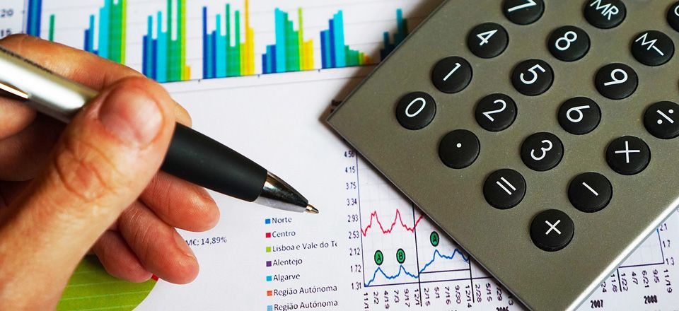 Repsol International Finance. View of a calculator, a hand holding pen and a number of documents with graphs