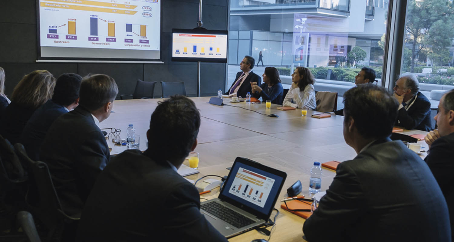 Several people in a conference room looking at a laptop with graphs