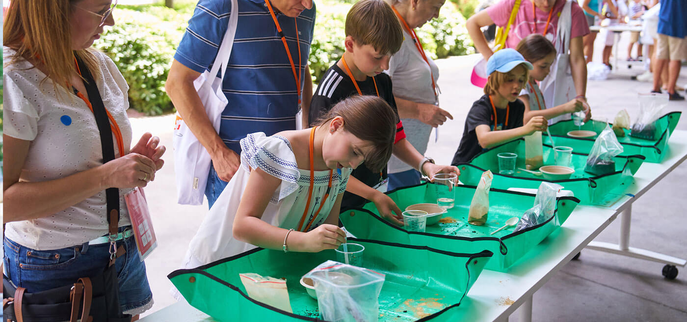 Participantes observan muestras naturales con microscopios en una actividad de descubrimiento de la microfauna urbana.