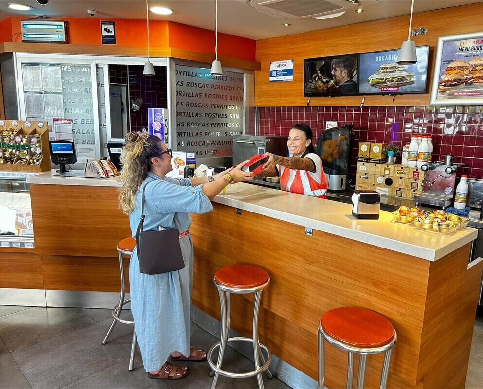 Sara Barcala, responsable de una estación de servicio de Repsol en la A-381, en Jerez de la Frontera, atiende a una clienta en el mostrador.