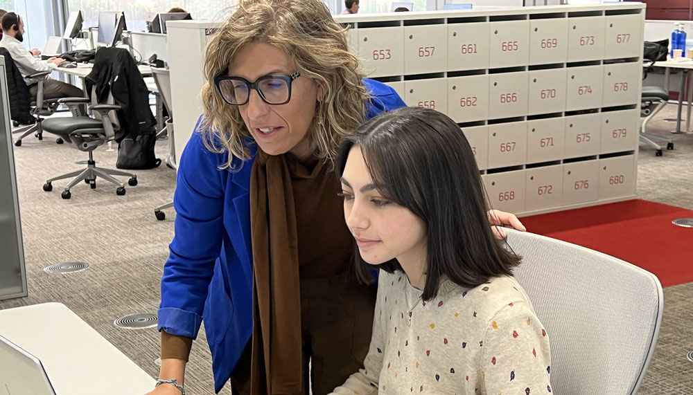 Una estudiante de química mirando una pantalla de ordenador, acompañada por su tutora