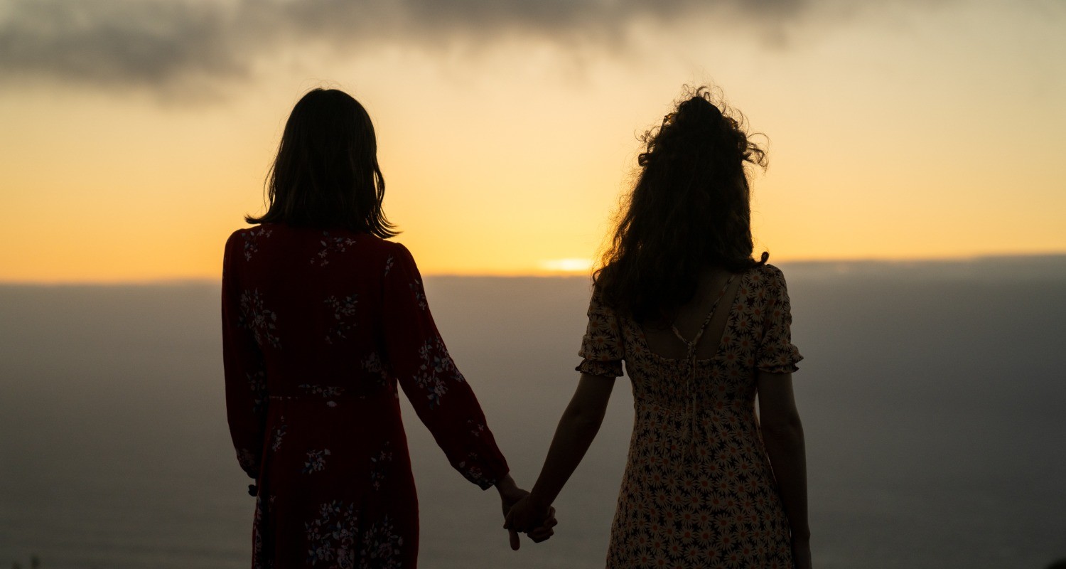 Two girls with their backs turned hold hands