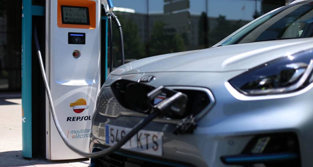 A woman watches an electric car recharging