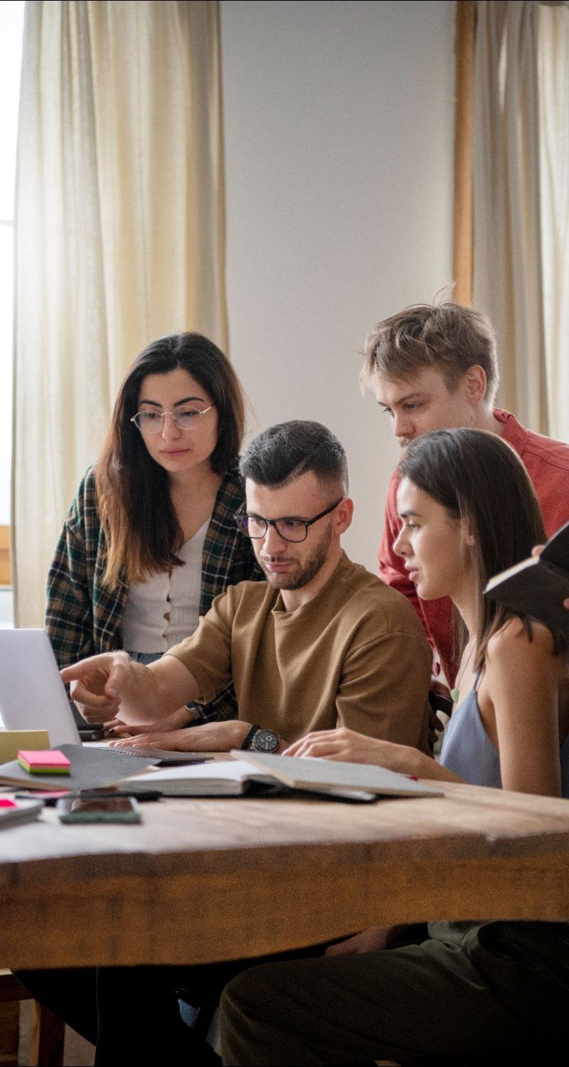 Four students gathered around a laptop computer.