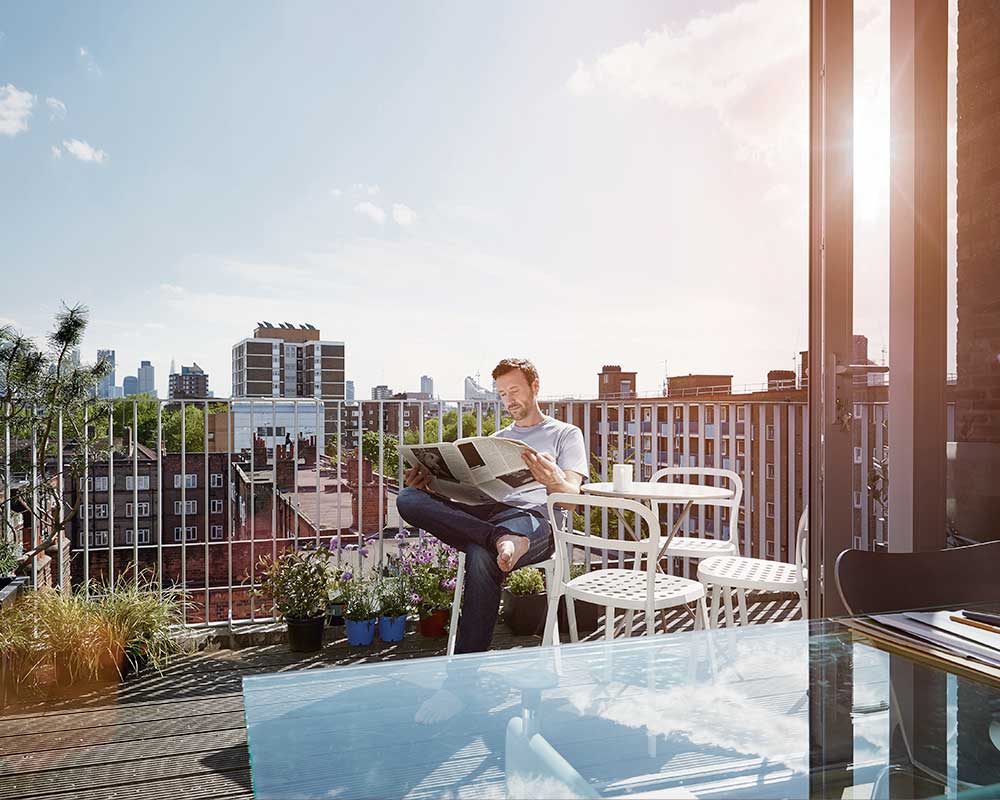 Hombre leyendo un periódico en el balcón de su comunidad solar