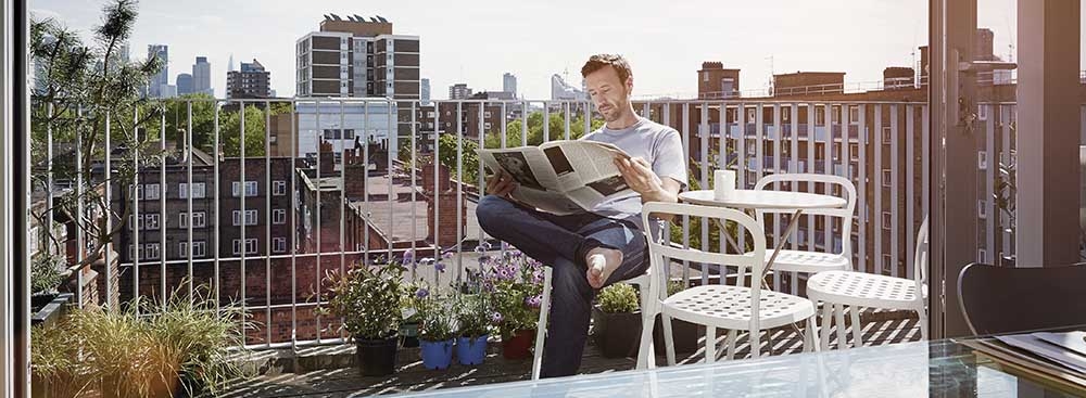 Un hombre lee el periódico en la terraza de su casa
