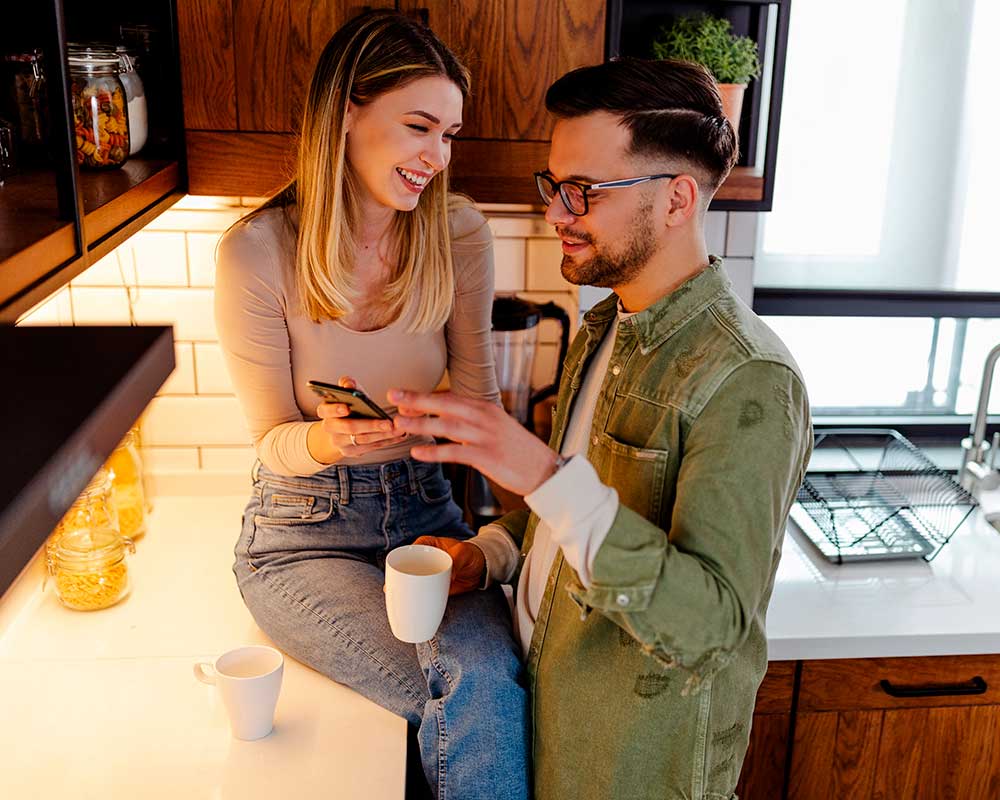 Happy couple in the kitchen using a smartphone