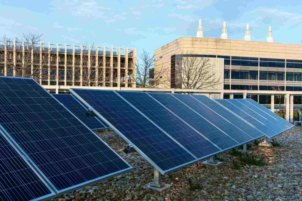 Image of a solar panel with a wind turbine in the background