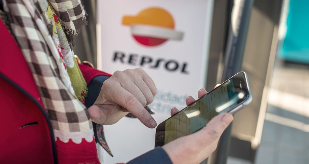 People using a cell phone with a Repsol logo in the background