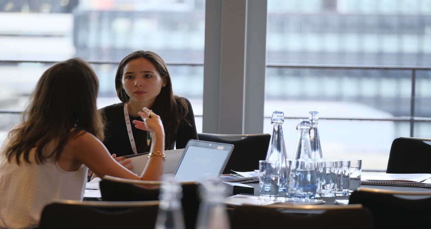 Female employees in an office chatting in front of computers