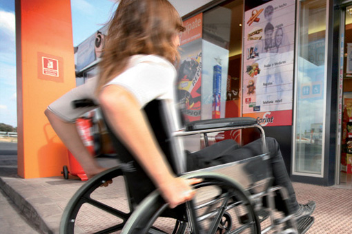 Different abilities. A person in a wheelchair enters a Repsol service station via a lowered step