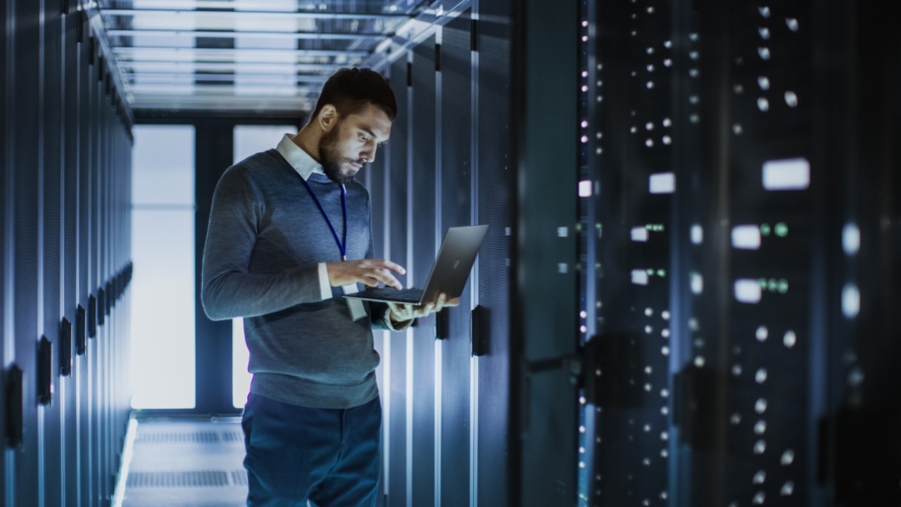 a big data analyst analyzing data in front of some servers