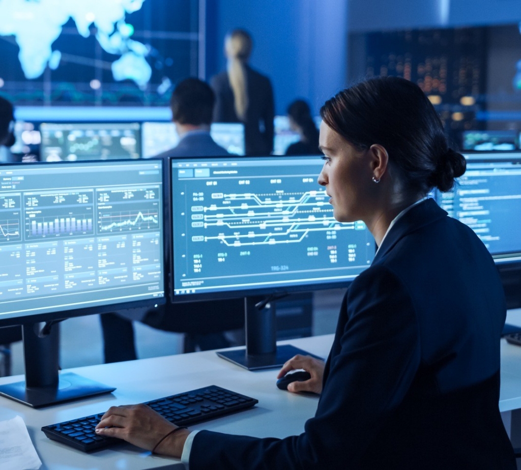 A woman working on several computer screens