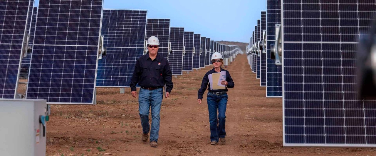 Dos operarios manejando un panel solar del proyecto de Repsol Jicarilla 2