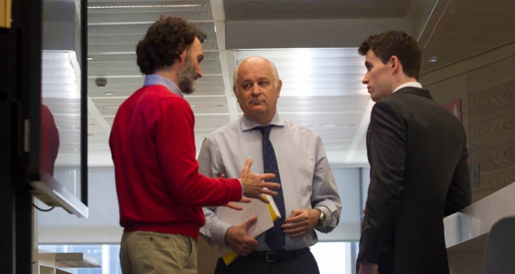 Three men talking in a hallway. Values