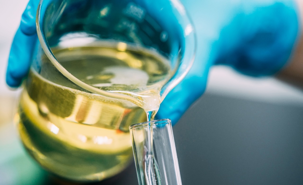 Bote de lubricante volcándose en una probeta