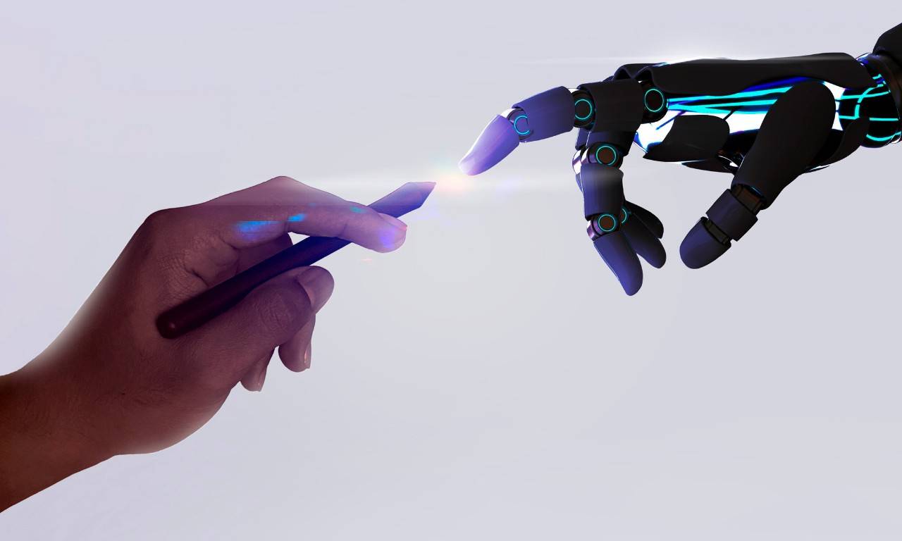 The hand of a person meets the hand of a machine as a sign of union between the virtual and the physical worlds