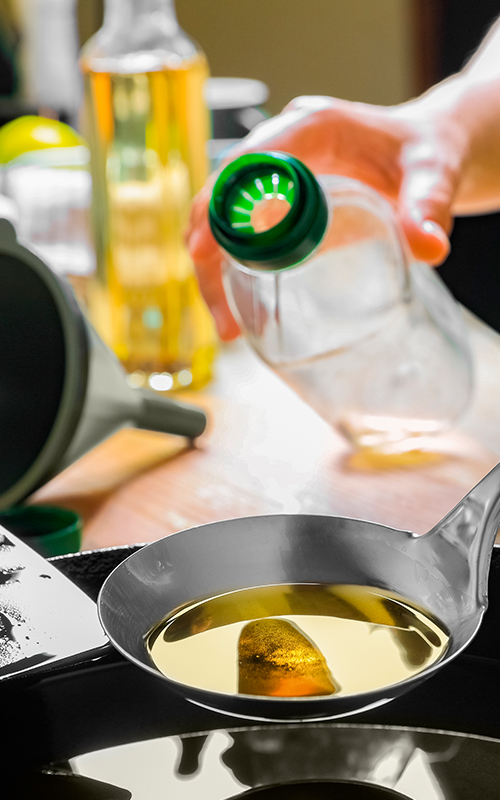 A person pouring oil on a frying pan