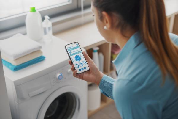 woman using an app to measure the consumption of her household appliances thanks to smart grids