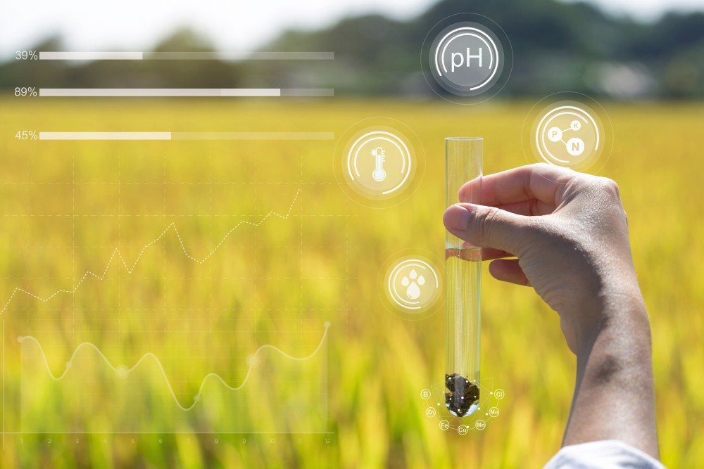 a hand holding a beaker in front of a field of wheat with scientific icons superimposed