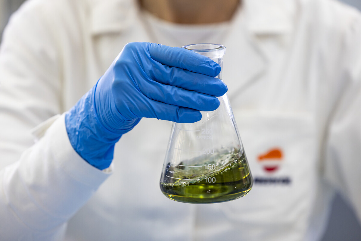 a chemist holding a beaker with a green liquid