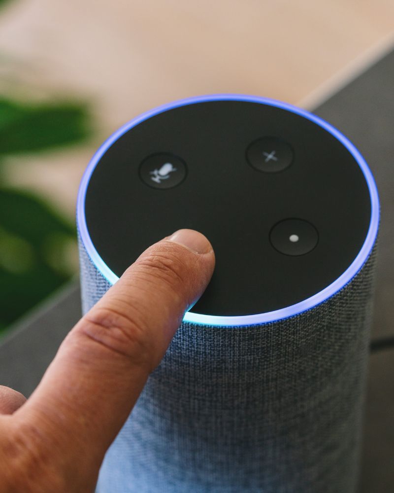 A finger touching a voice assistant device