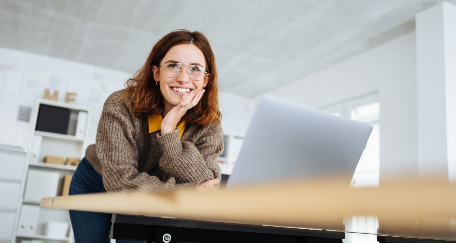 A woman smiling while looking at her laptop