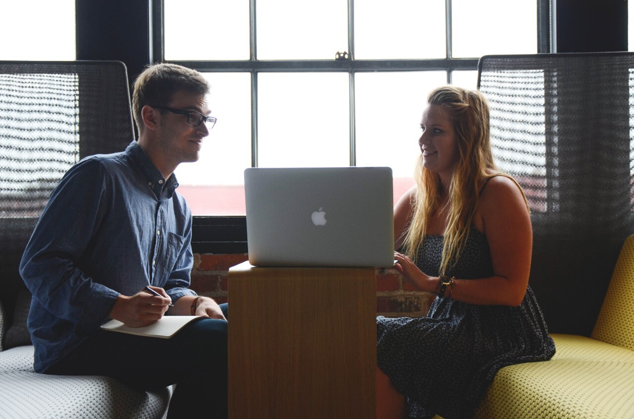 two colleagues looking over business plans on a laptop