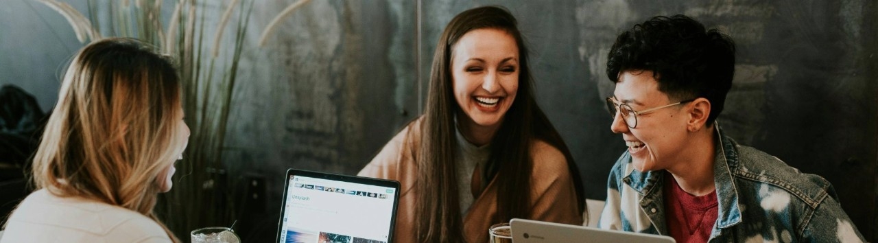 Grupo de personas sentadas trabajando y riéndose
