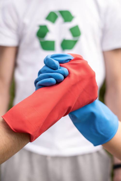 Two locked hands wearing gloves with the recycling symbol in the background