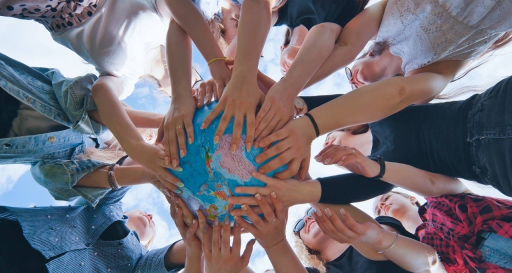 Numerous people holding up a globe