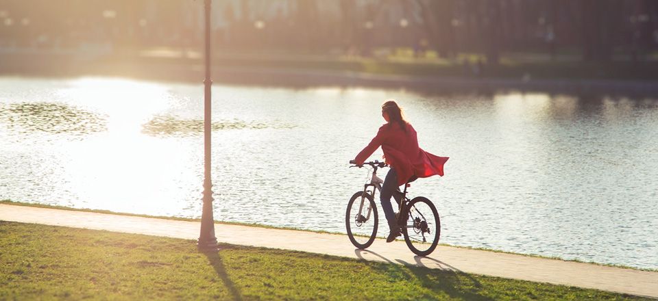 A woman cycles along a riverbank