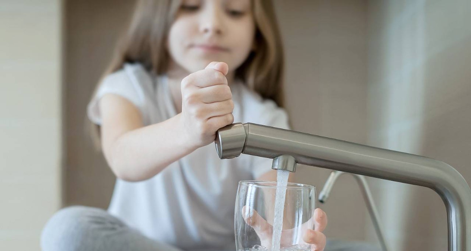 Una niña ahorrando agua con un grifo moderno para cuidar el medio ambiente