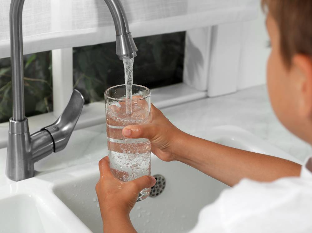 A child filling up a glass with water