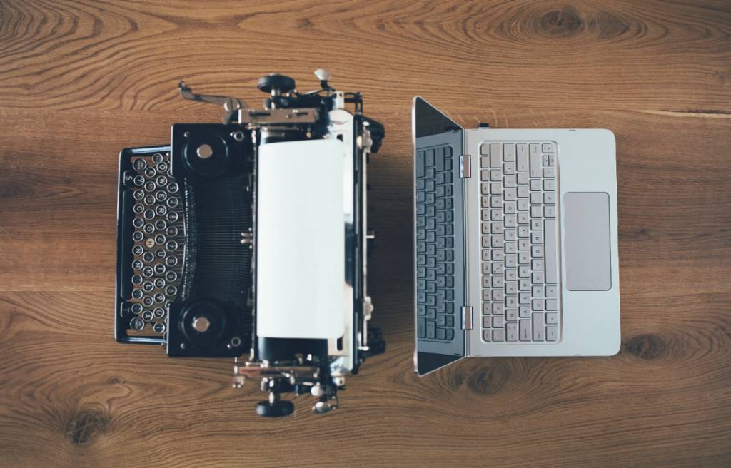 A typewriter and a laptop on a table