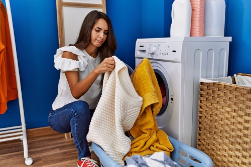 A woman putting clothes in a washer