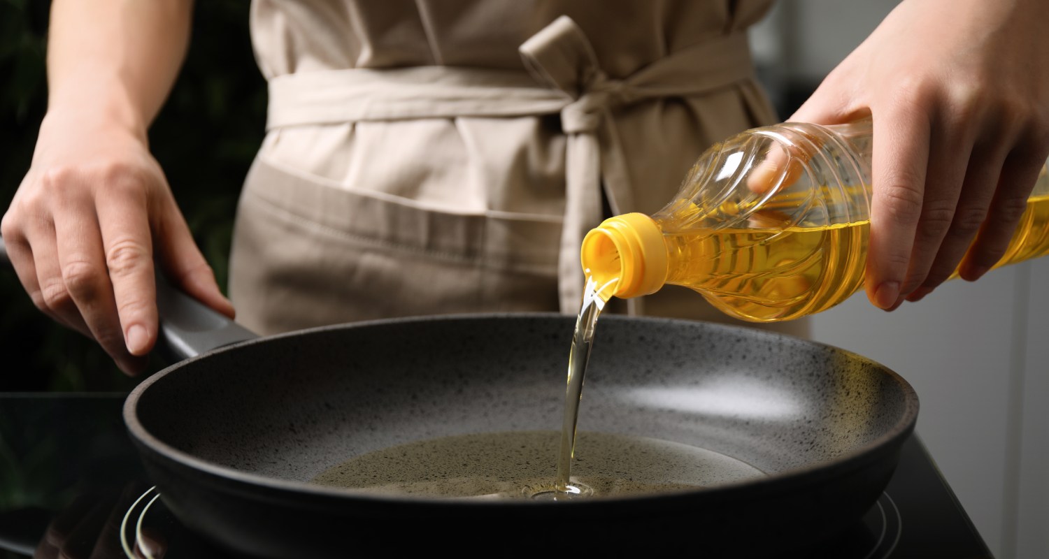 A person pouring oil into a frying pan
