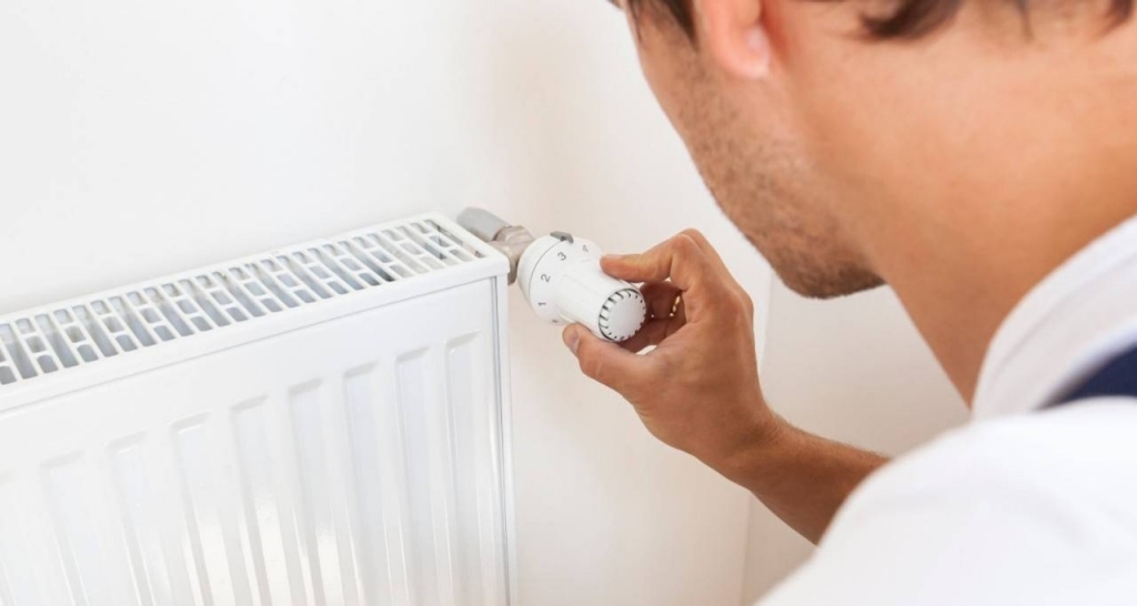 Una persona regula el termostato de un radiador