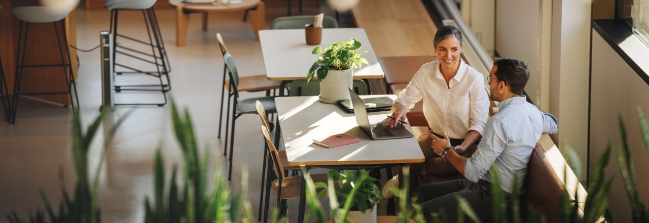 Two people talking next to a computer