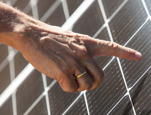 A hand pointing at a solar panel