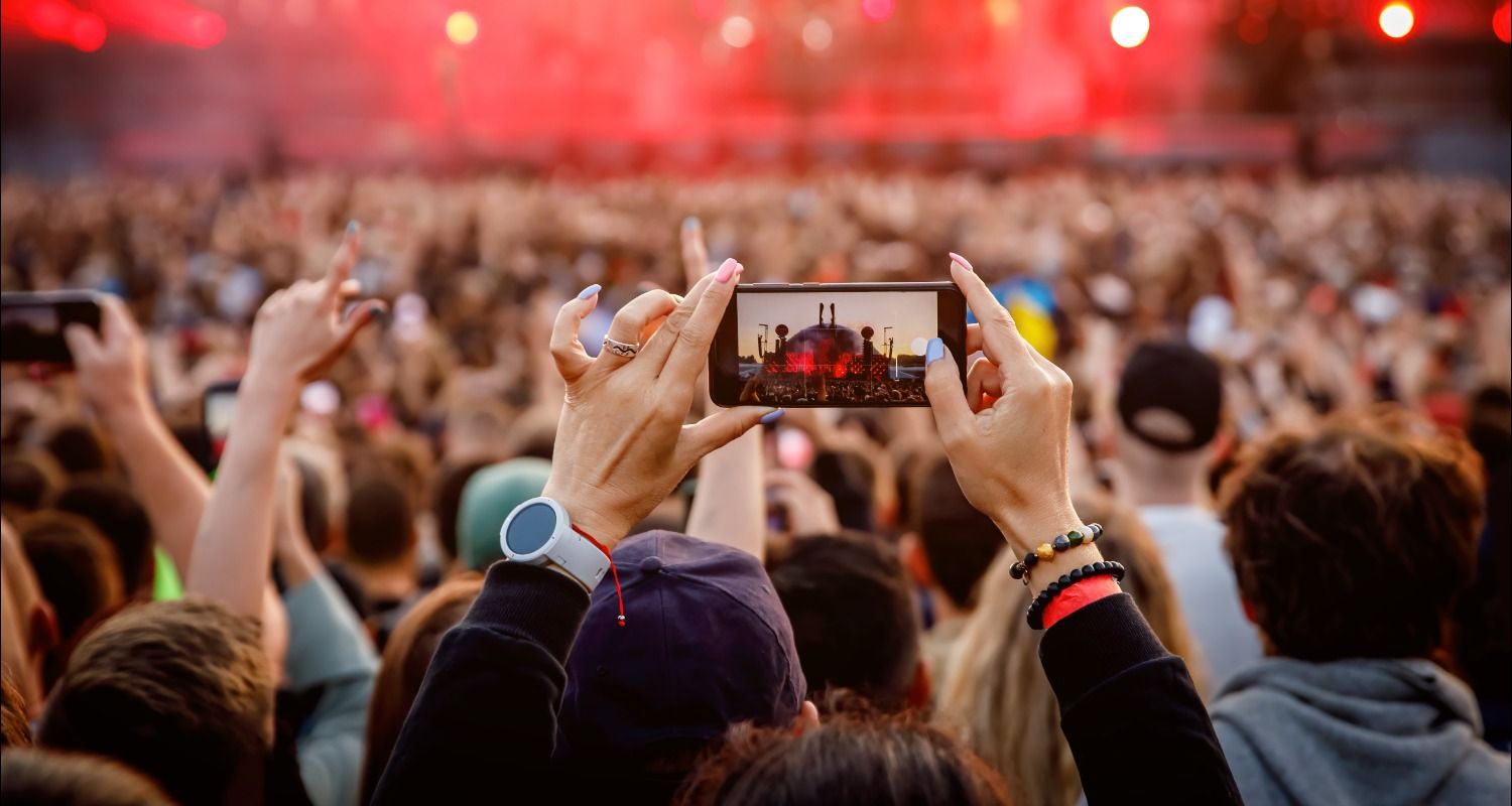 Manos sujetando un móvil en un concierto