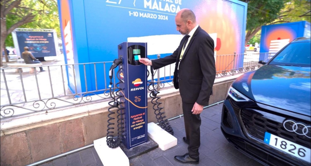 Hombre recargando coche eléctrico en párking subterráneo