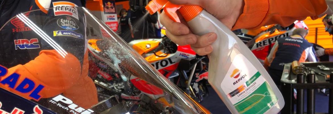 Detalle de una mano limpiando el parabrisas de una moto