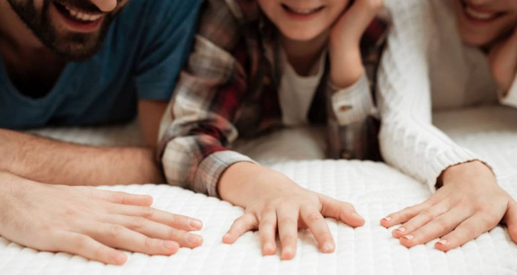 Una familia colocando las manos sobre un colchón