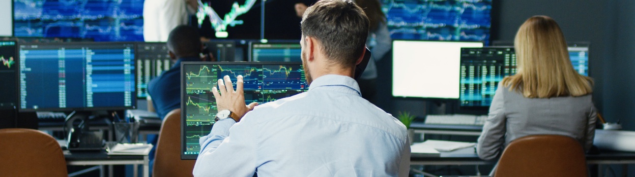 Several people analyzing data and graphs on computer screens